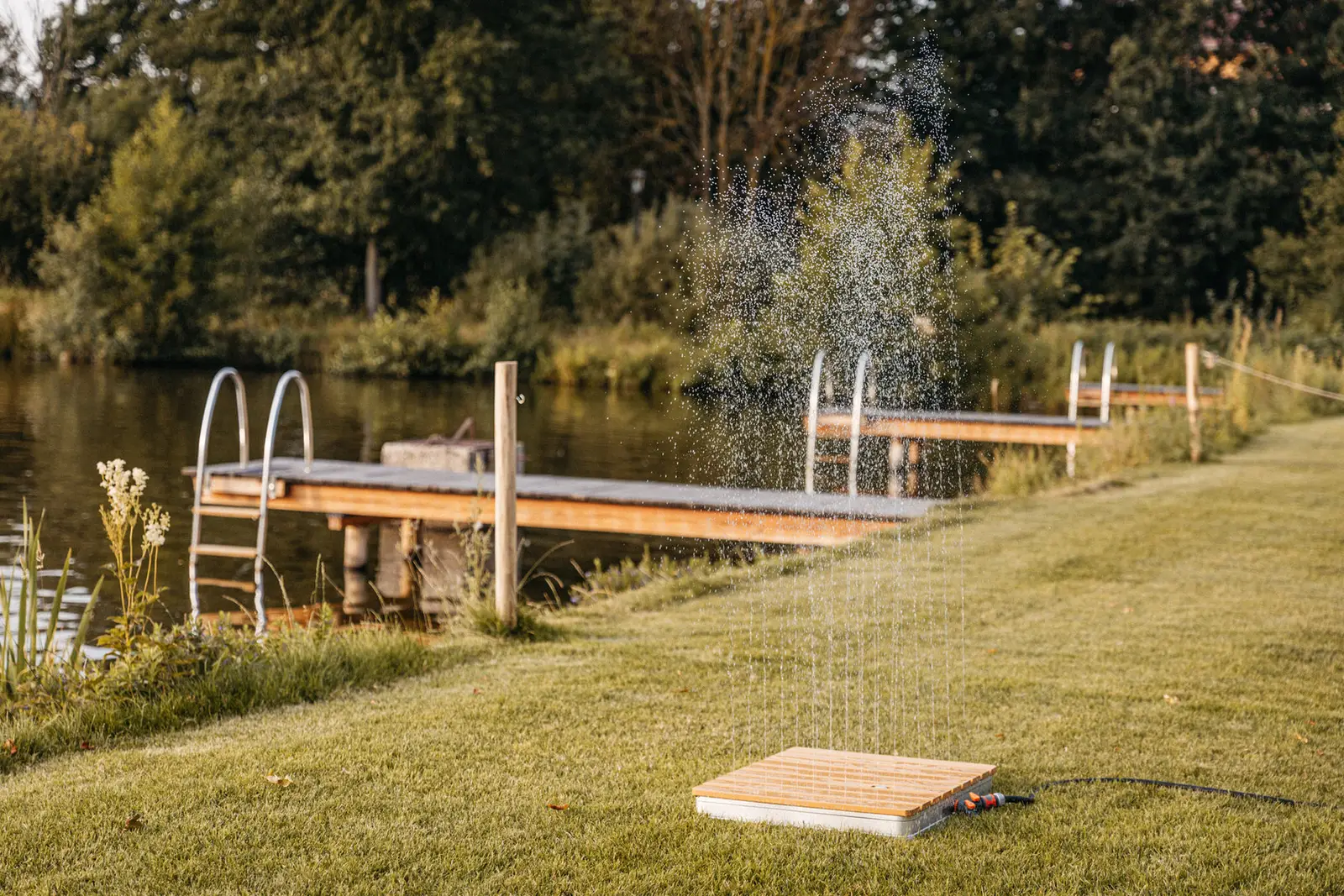 Gartendusche auf dem Rasen vor dem Steg