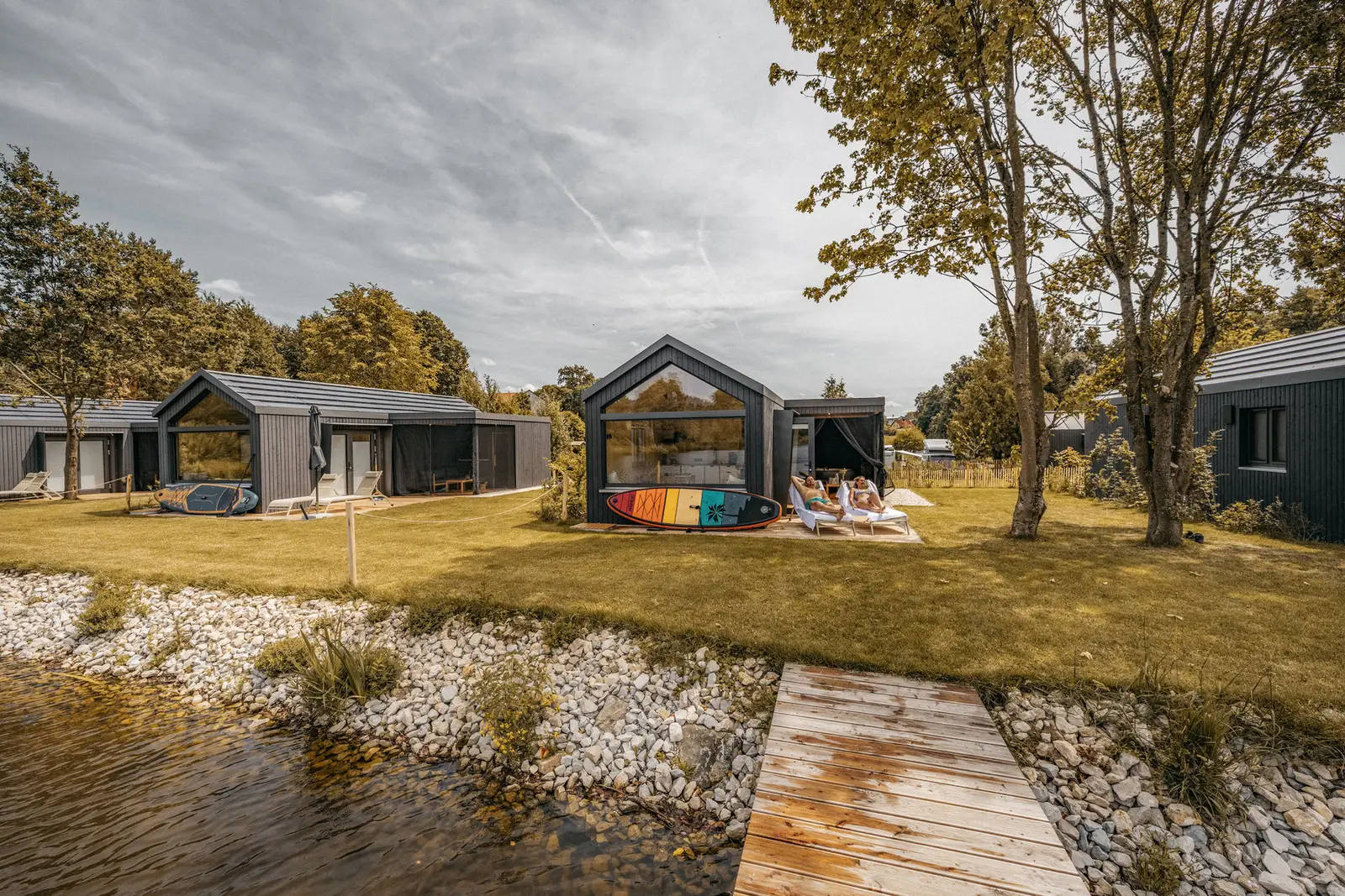 Cabins mit dunkler Holzfassade am Ufer des Erlenweihers