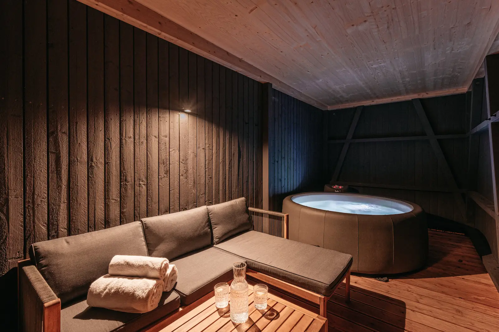 Whirlpool und Lounge auf der überdachten Terrasse bei Nacht