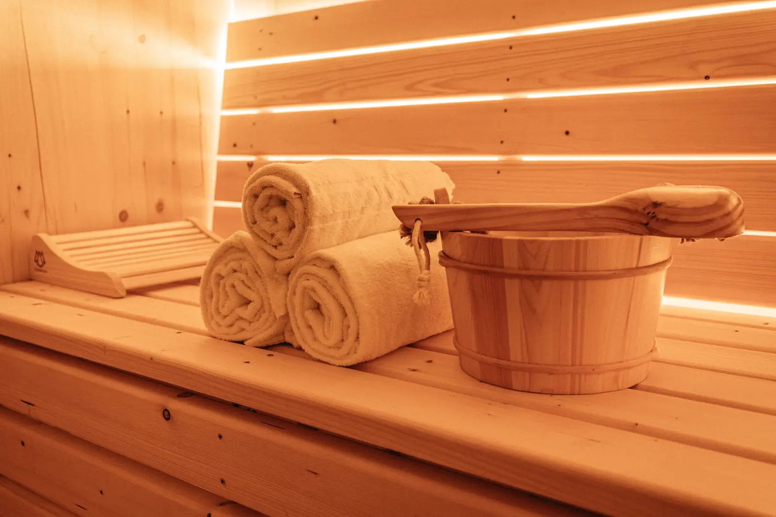 Finnische Sauna mit gerollten Handtüchern und Aufgusskübel