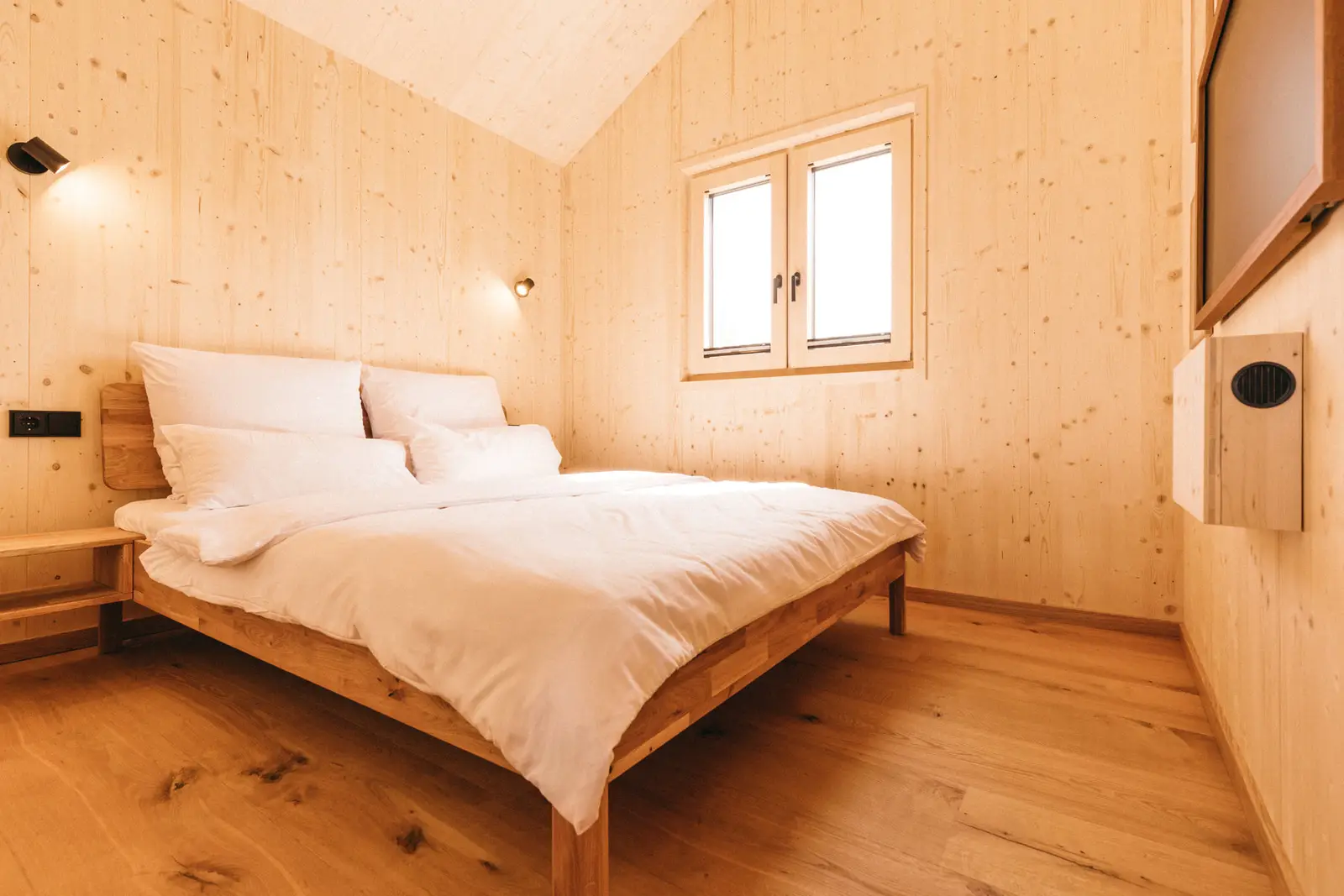 Queen-Size-Bett zwischen hellen Holzwänden